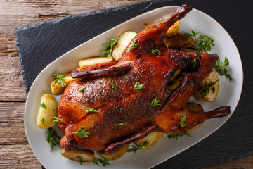 Delicious whole baked duck with apples close-up on a platter. horizontal top view © FomaA