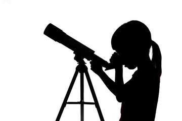 Silhouette of little girl looking through a telescope