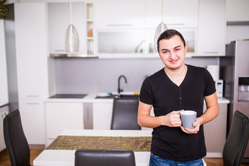 Portrait of handsome man drinking coffee in home kitchen