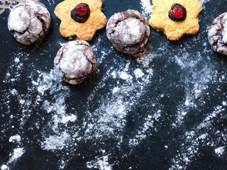 Festive cookies on a black kitchen board with powdered sugar