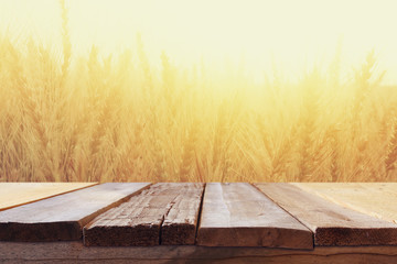 wood board table in front of field of wheat on sunset light