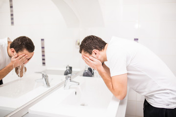 Obraz premium Handsome man washing face in bathroom in morning