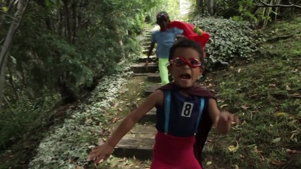 2 Superhero kids run into a heavily wooded backyard garden