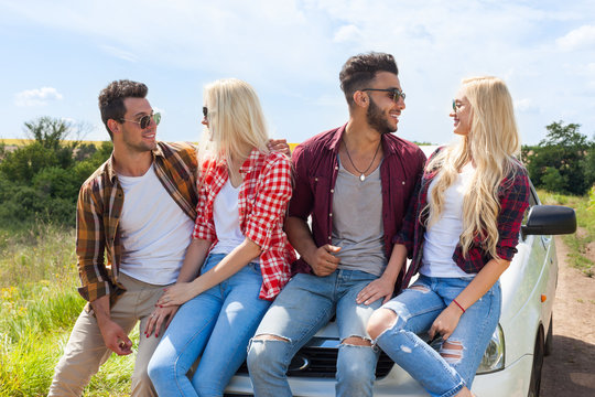Friends sitting on car outdoor countryside people smile summer day trip