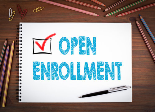 Open Enrollment. Notebooks, pen and colored pencils on a wooden table.