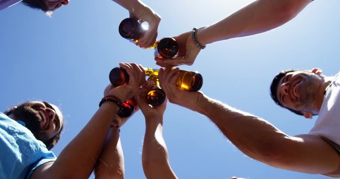 Group of friends toasting beer bottles at outdoors barbecue party