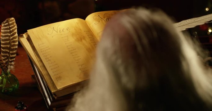Santa Claus dips a quill in ink to add a name to the Naughty List. Over Shoulder