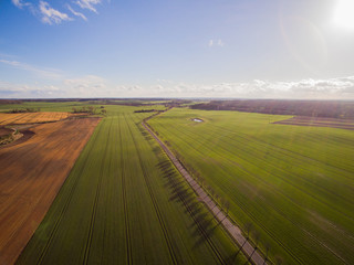 Aerial view of a country road with beautiful agricultural fields under blue sky at late afternoon -...
