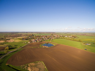 Fototapeta na wymiar aerial view of a smal village with beautiful agricultural fields under blue sky - germany