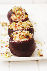 Baked beets with cheese filling and sprouts on white dish