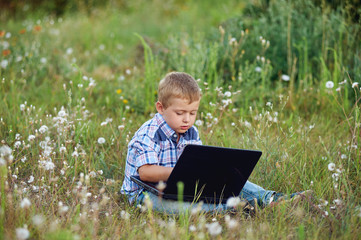 boy with laptop on the nature . The concept of preschool education