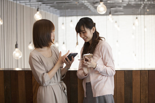 Women are talking while watching smartphones
