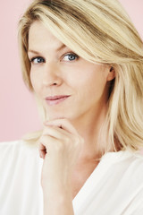 Naklejka premium Thoughtful blond in pink studio, portrait