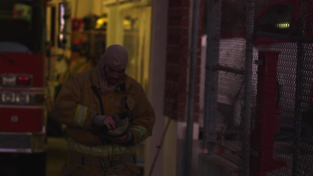Slow motion, firefighter puts on gear outside fire station