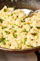 Scrambled eggs with onion in black pan
