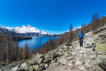 Fototapeta premium Alpine trekking on the Swiss Alps a girl hiking with a large lake in the background