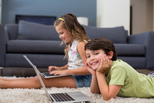 Siblings using laptop in living room