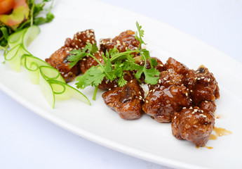 Sauteed pork ribs with seasame and herbs on white dish