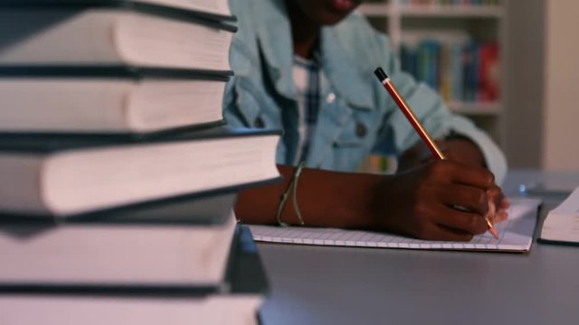 Close-up of book stack with schoolgirl studying in background