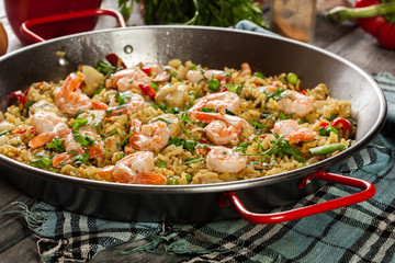 Traditional seafood paella with shrimp, fish and chicken seved in paellera