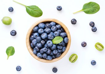 Fresh blueberries in wooden bowl on white background. Top view. Fresh food background © Vladislav Noseek
