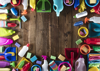 Variety of colorful house cleaning products, rustic wooden table, top view shot. Spring cleanup concept. 
