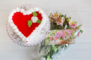 Red and white heart-shaped cake and lily flowers with greeting card