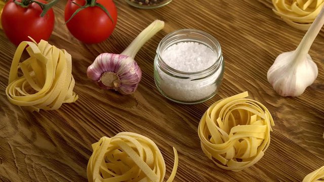pasta, oil, tomatos and garlic on wooden background