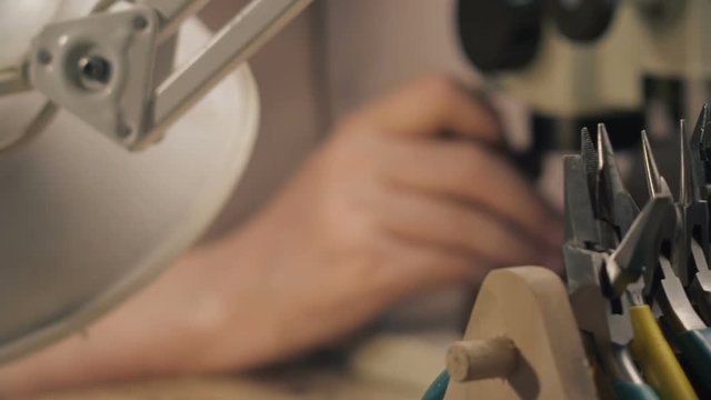 A jeweler is working by the microscope