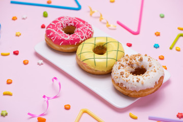 Party. Different colourful sugary round glazed donuts and bottles of drinks on pink background.