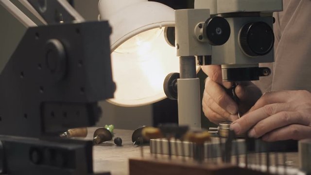 A jeweler is working by the microscope