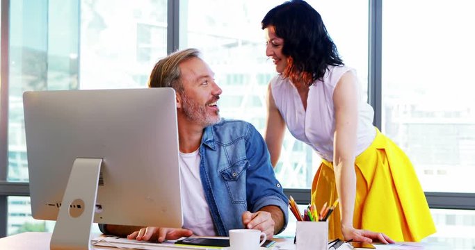 Male and female graphic designers working together at desk