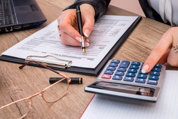 Woman filing individual income tax form 1040, with calculator. close up.