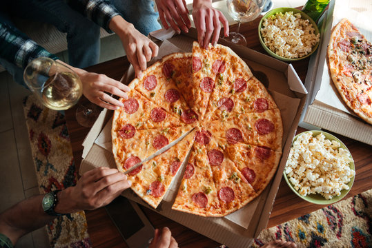Top view of a group of friends eating big pizza