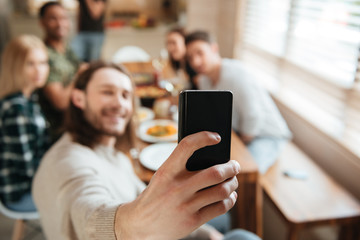 Man taking a selfie photo with friends in the kitchen