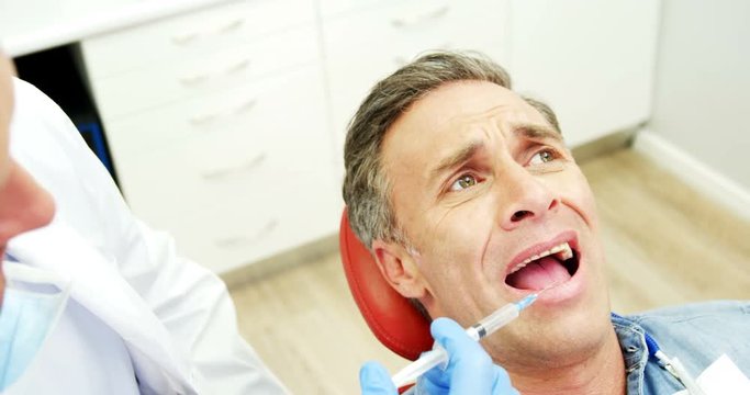 Scared man receiving injection from dentist