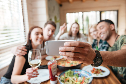 Group of friends eating and taking selfie at the table