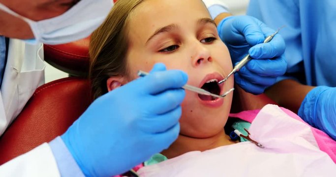 Mid-section of dentist and nurse examining a young patient with tools