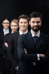 group of confident business people standing in row isolated on black