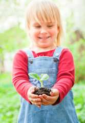 Little girl holding seeding with ground