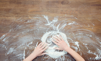 top view of child making pizza dough on wooden tabletop