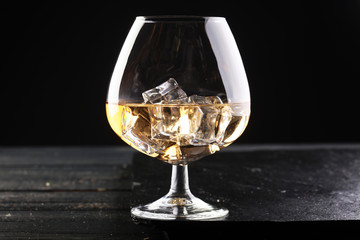 glass of whiskey with ice on a wooden