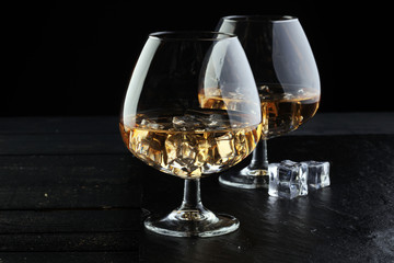 glass of whiskey with ice on a wooden