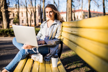 Girl using a laptop on a bench in spring park