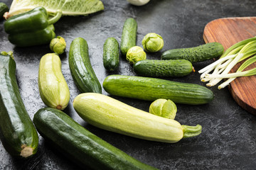 different green fresh seasonal vegetables on black table top background