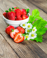 Fresh strawberries in a bowl on wooden table.