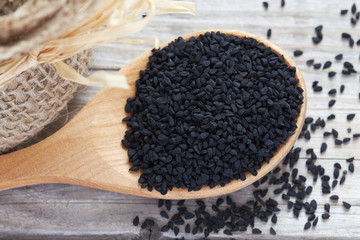 Black cumin seed (Nigella sativa) in wooden spoon. Top view