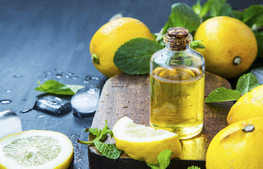 Lemon essential oil bottle with lemons fruits and mint leaves
