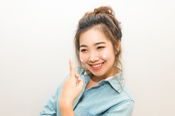 Young asian woman smiling and applying moisturizing cream on her face