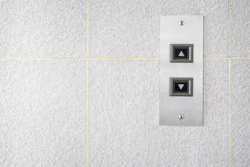 The modern lift button panel on stone tite wall close up background.